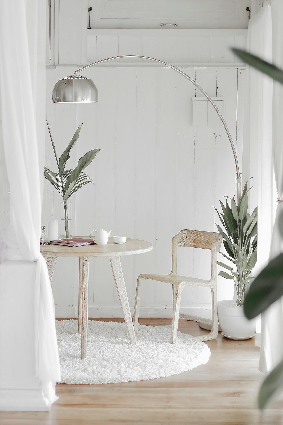 Bright minimalist room with an arc floor lamp over a wooden table